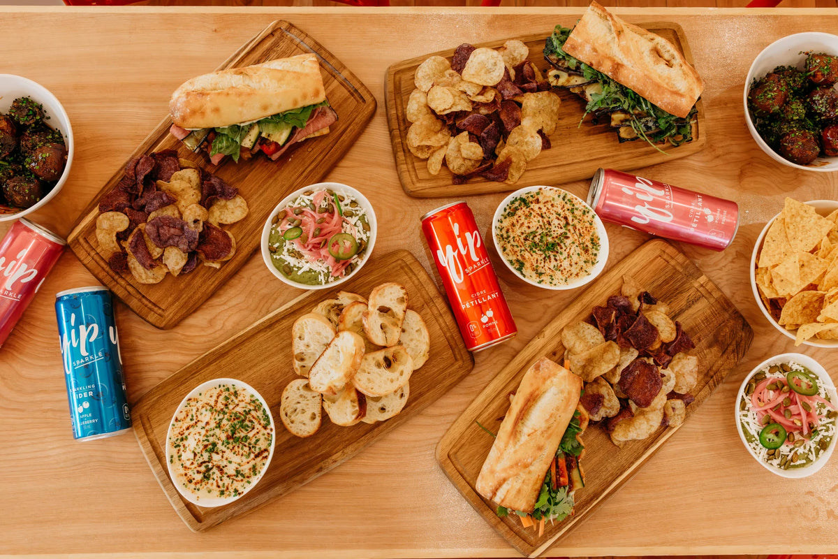 The Press sandwiches, chips, dips, glazed potatoes and Yip cider arranged for sharing