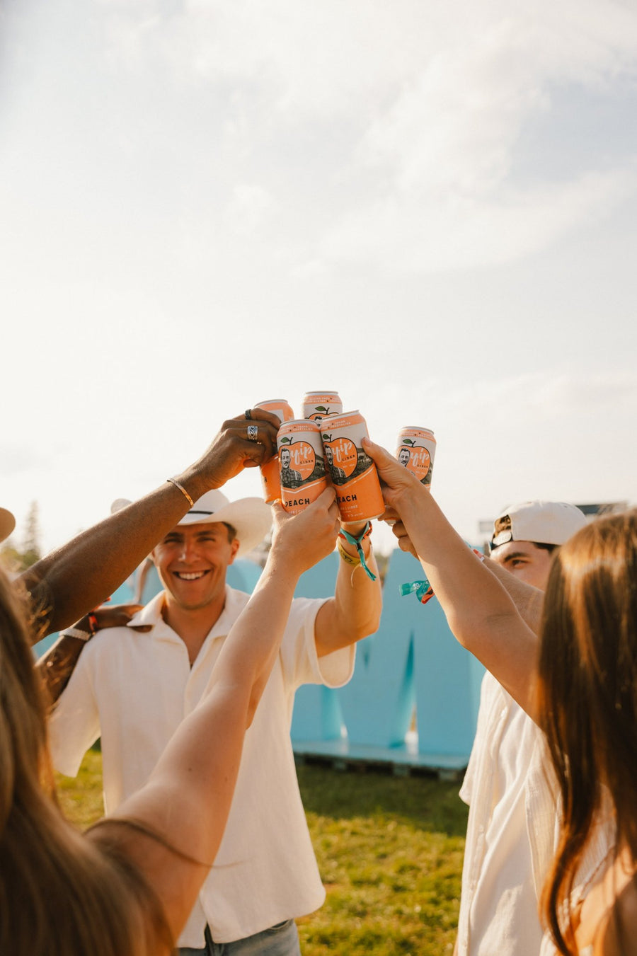 Friends raising five cans of Yip Peach in a cheers at Cavendish Beach Music Festival