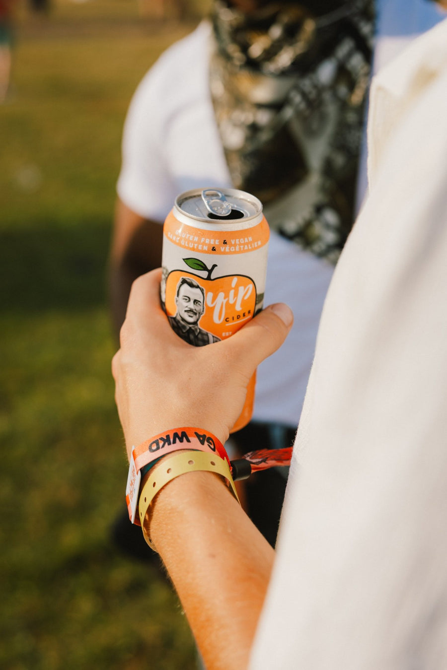 A festival-goer with a CBMF wristband holding an open can of Yip Peach